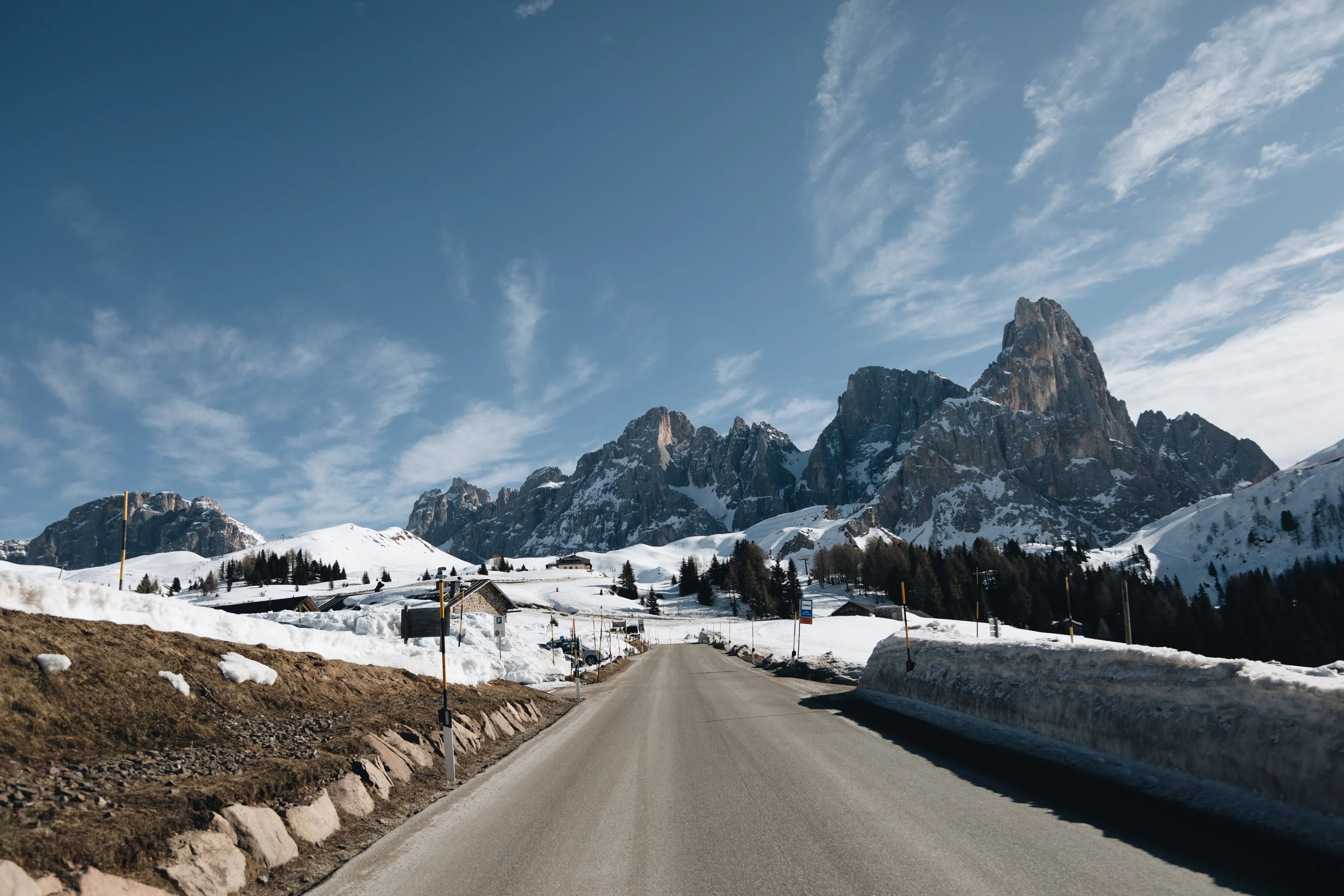 Eine Straße und die Dolomiten mit Schnee im Hintergrund